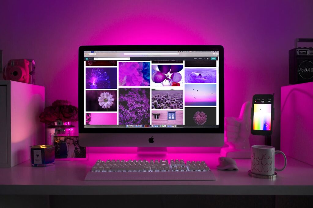 pexels photo 1779487 Modern desk setup with neon lighting and a desktop computer displaying colorful images.
